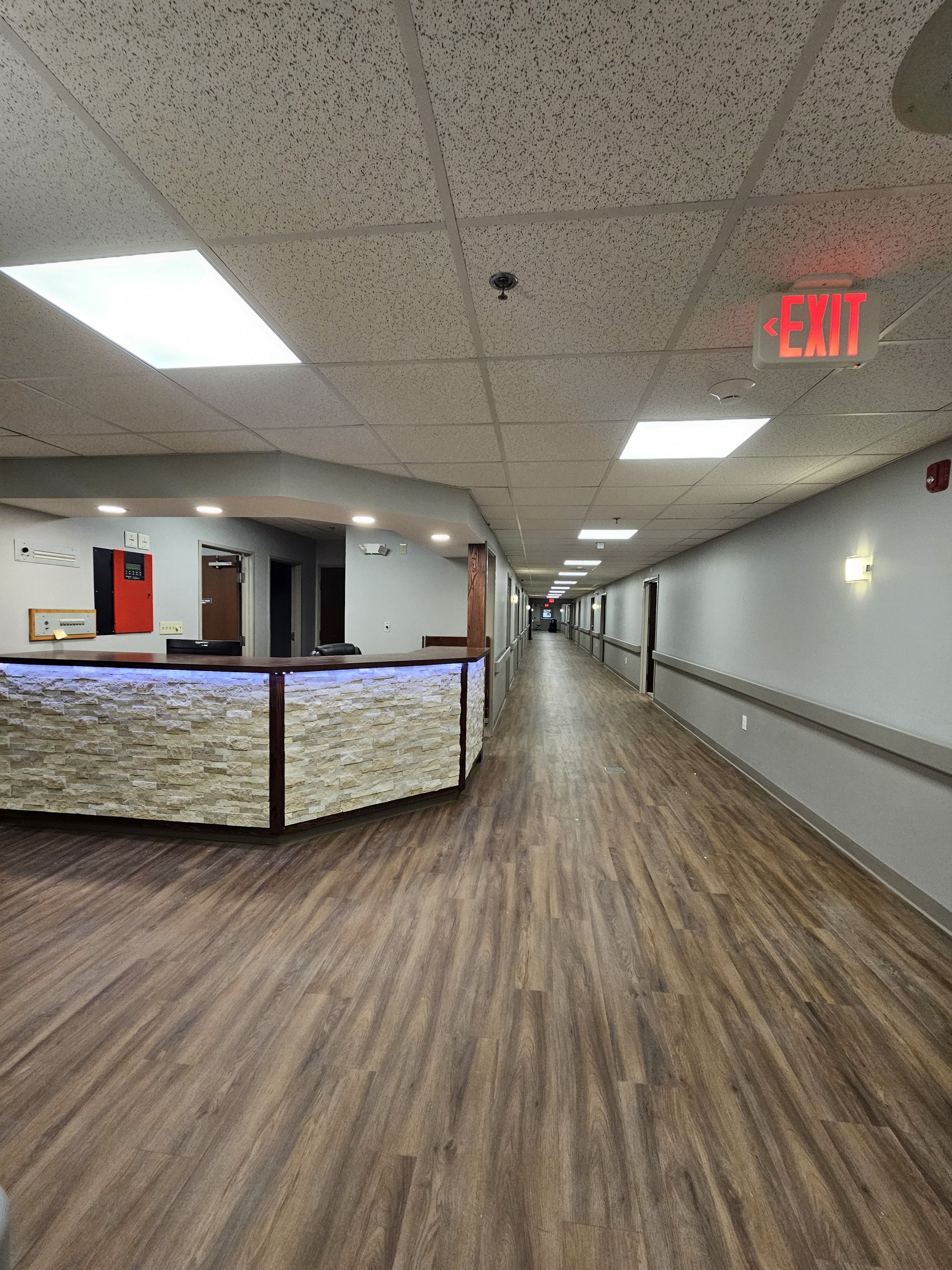 Corridor after restoration: fully repaired hallway with new flooring, paint, and lighting