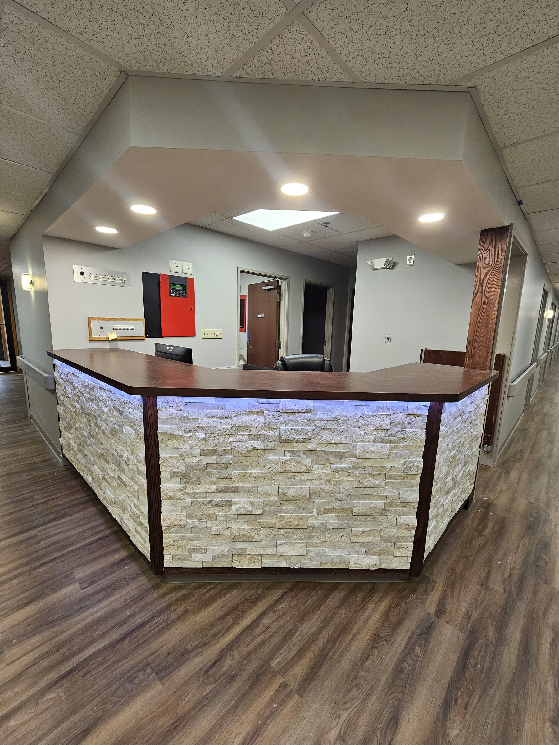 Nurses station after renovation: finished stacked-stone reception desk with accent lighting and new flooring